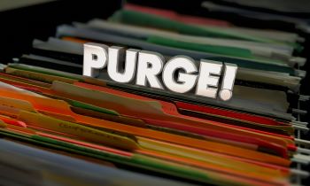 Multi-colored file folders in file cabinet with the word "PURGE" superimposed at top of files.