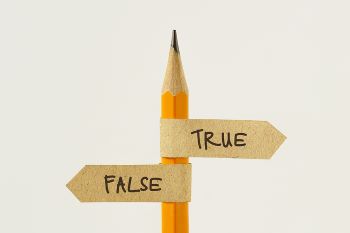 Sharpened yellow pencil wrapped with tiny paper flag pointing left that says "FALSE" and tiny paper flag pointing right that says "TRUE"