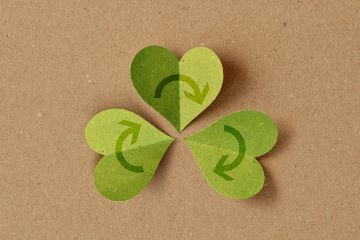 Recycling symbol with heart shaped leaves on recycled paper background