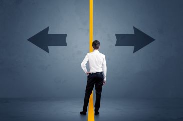 Back view of a business person choosing between two options indicated by arrows pointing in opposite directions, separated by a yellow line