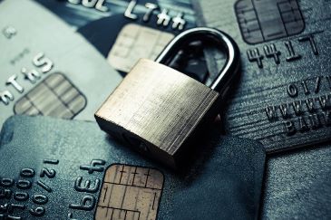 A security padlock sits on top of a scattered pile of credit cards.